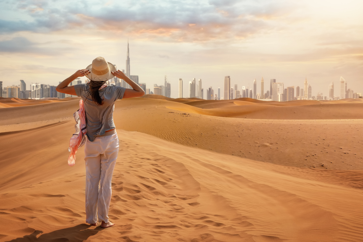 Turystka na pustyni w Dubaju patrząca na panoramę miasta